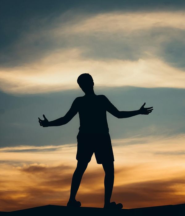 Silhouette of a person in a yoga warrior pose against a vibrant sunset.