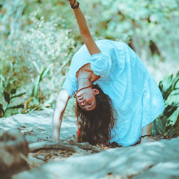 Woman performing a graceful yoga pose in a tranquil environment.